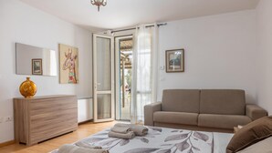 Un dormitorio con cama, sofá, cómoda de madera y puerta corrediza de vidrio que da a un espacio al aire libre.