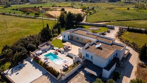 Una casa moderna con piscina, un porche cubierto y vistas del campo circundante.