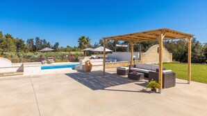 Un espacio de estar techado al aire libre con piscina y sillones de descanso.