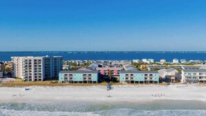 Un hotel frente a la playa con varias construcciones, una playa de arena y el océano al fondo.