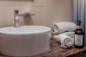 Ein Badezimmer mit einem weißen Waschbecken, einem Handtuch und einer Flasche Duschgel.