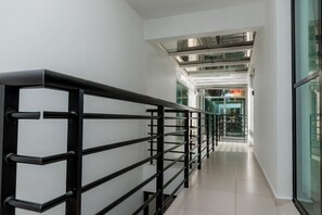 A corridor with a black metal railing, glass doors, and a modern interior design. - Mojarra Marazul: Suite Boutique with Terrace in Cancún (Cancún)