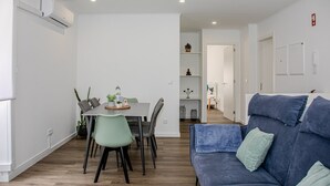 A modern living space with a dining area, a sofa, and a hallway leading to other rooms.