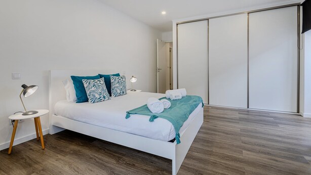 A modern bedroom with a bed, bedside lamp, and a view of a sliding door closet.