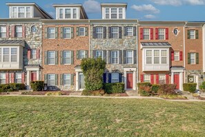 A row of townhouses with stone and brick facades, multiple windows, and a well-maintained lawn.