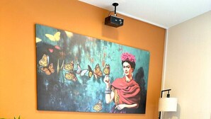 Een woonkamer met een blauwe bank, een schilderij van vlinders, een lamp en een kamerbreed tapijt met een patroon.