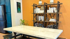 Een eettafel met banken, een boekenkast en een keukenhoek.