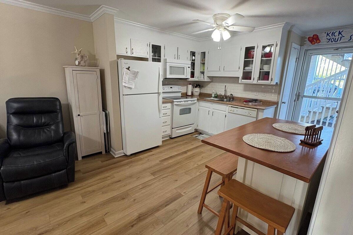A kitchen with white cabinets, a black chair, and a wooden table with placemats.