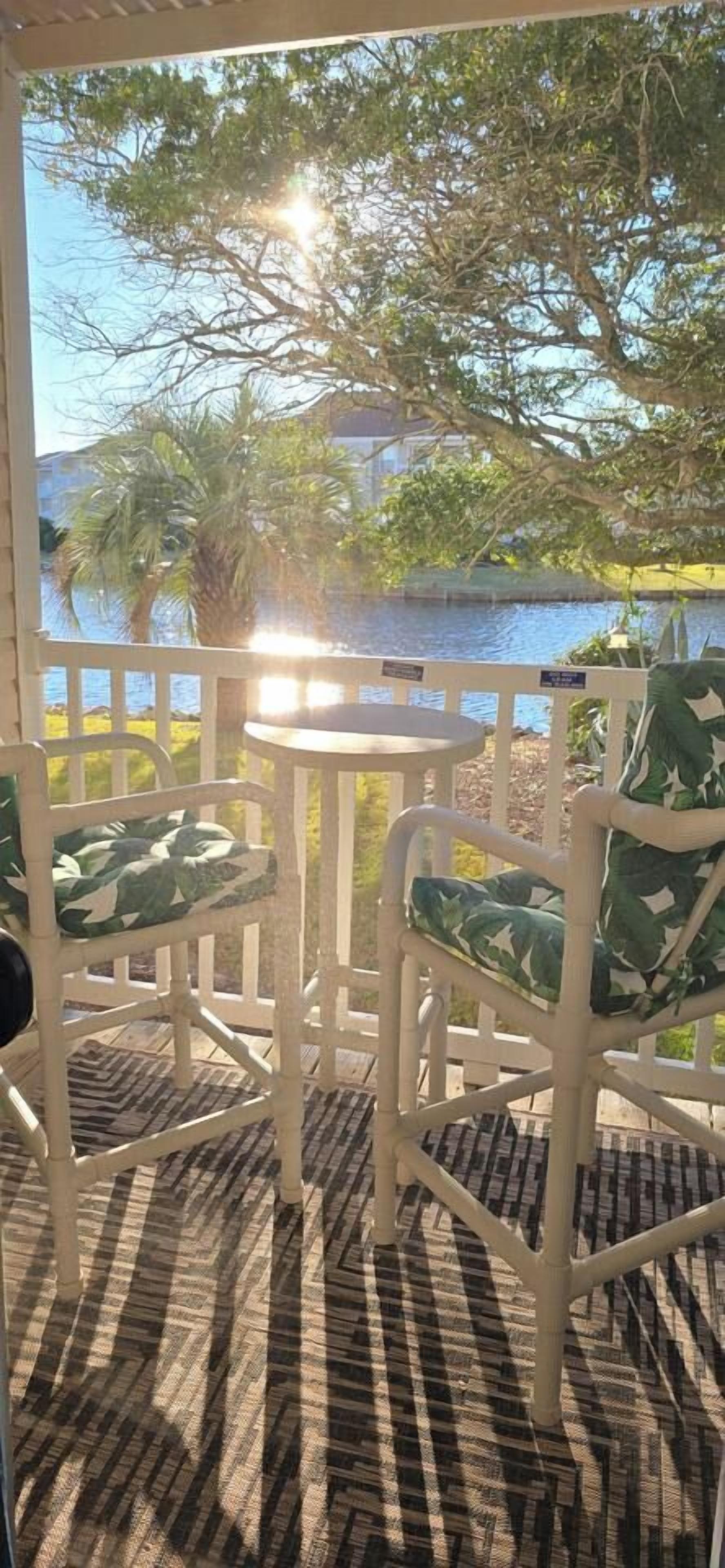 A covered outdoor seating area with white metal chairs and a patterned floor.