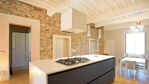 Uma cozinha moderna com uma ilha central, uma parede de pedra e um espaço de refeições com mesa e cadeiras.