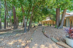 A pathway lined with trees leading to a building with a covered porch. - Rayford Crossing RV Resort (Spring)