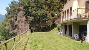 Ein Gebäude mit Balkon, einer sanften Grünfläche und einem Holgitter.