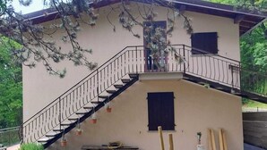 Ein zweistöckiges Gebäude mit Treppe, einer kleinen Bank und Baumaterialien.