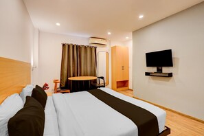 A hotel room with a bed, a small table, a TV, and an air conditioning unit. - Townhouse Sarjapur Near Bellandur (Bengaluru)