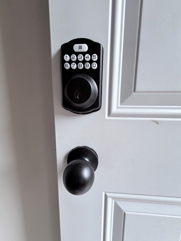 A door with a black electronic keypad and a round doorknob.