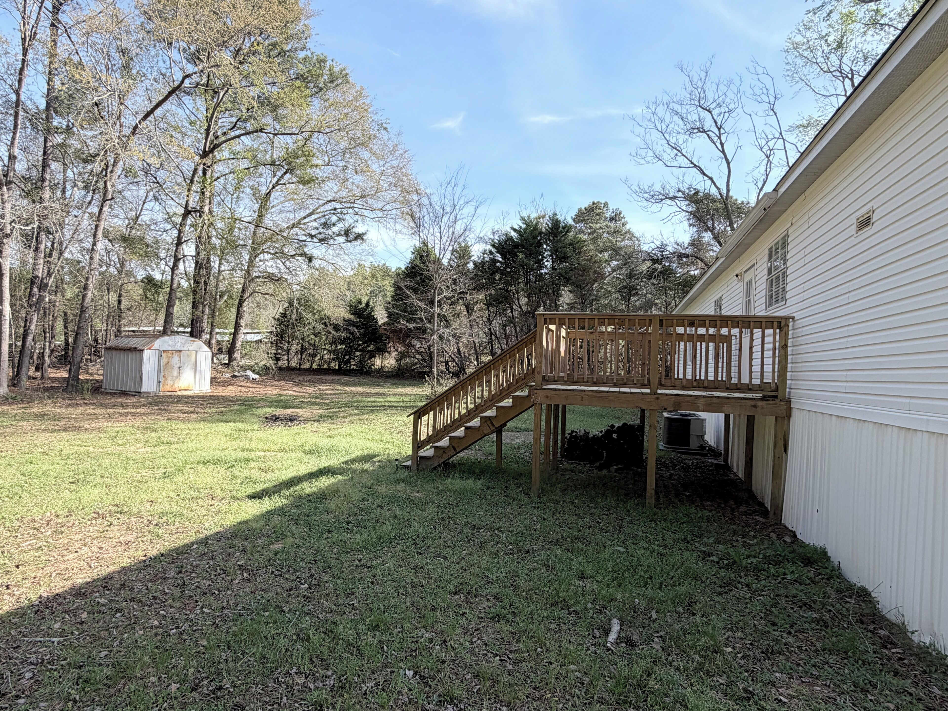 A backyard with a wooden deck, a small shed, and a house.