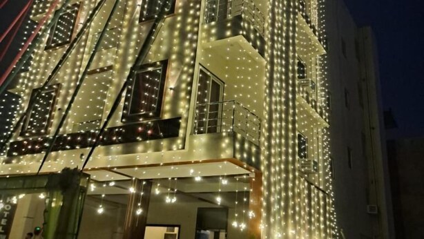 A multi-story hotel with balconies and string lights. - Hotel Shyam Mahal (Khatoo)
