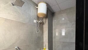 A bathroom with a toilet, sink, shower, and a blue bucket. - Hotel Shyam Mahal (Khatoo)