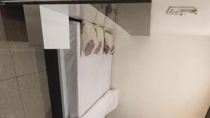 A room with a bed, a wooden bench, a tiled floor, and a wall-mounted light fixture. - Hotel Shyam Mahal (Khatoo)