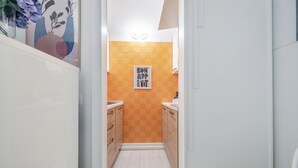 Eine schmale Küche mit Holzschränken, einer Fliesenrückwand und einem gerahmten Plakat an der Wand.