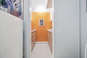 Eine schmale Küche mit Holzschränken, einer Fliesenrückwand und einem gerahmten Plakat an der Wand.