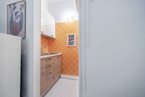 Eine schmale Küche mit Holdekor-Schränken, einer weißen Arbeitsplatte und einer gefliesten Rückwand.