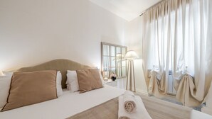 Ein Hotelzimmer mit Bett, Nachttisch, Lampe, Spiegel und Vorhängen.