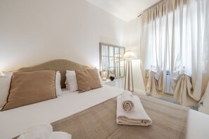 Ein Hotelzimmer mit Bett, Nachttisch, Lampe, Spiegel und Vorhängen.