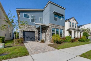 A modern two-story house with a stone facade, a garage, and a well-maintained lawn. - Cheerful Villa with Pool, Spa (Kissimmee)