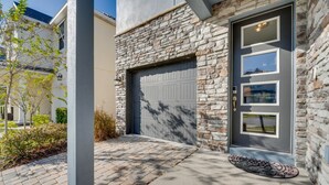 Ein Haus mit Natursteinfassade, einer Garagentür und einer Eingangstür mit kleinem Fenster.