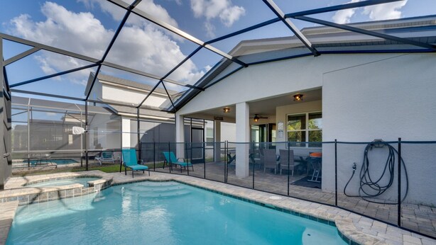 Ein Schwimmbad mit Glasveranda, Liegestühlen und einer überdachten Terrasse.