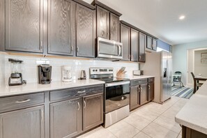 A modern kitchen with wooden cabinets, stainless steel appliances, and a tiled backsplash. - Cheerful Villa with Pool, Spa (Kissimmee)