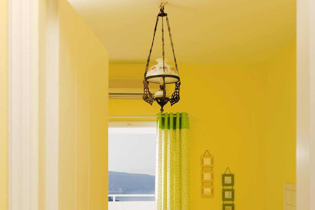 Et værelse med en seng, et vindue med udsigt, en dør og en hængende lampe.