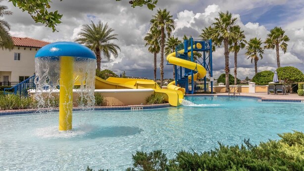 Una piscina con tobogán y fuente de agua.