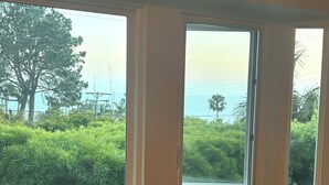 Une chambre à coucher avec un lit, une fenêtre et une vue sur la verdure et un plan d’eau.