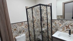 Un bagno con cabina doccia, servizi igienici e mobile lavabo con specchio.