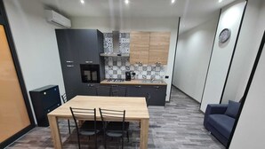 Una cucina moderna con zona pranzo, che include un tavolo e sedie in legno, un forno a incasso e una macchina da caffè.