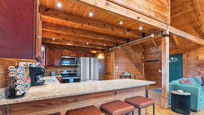 Ein Holzblockhaus-Innenraum mit Küche, Bar und Treppe.