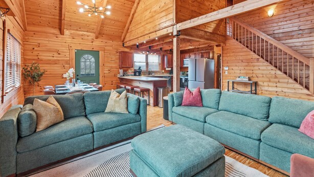 Ein Holzblockhaus-Interieur mit Wohnbereich, Küche und Treppe.