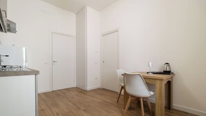 Een keuken met een koelkast, een houten tafel met stoelen en een koffiezetapparaat.