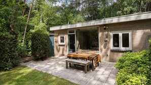 Een huis met een terras, een tafel met een tafelkleed met patroon, en een bank.