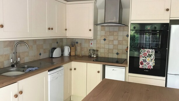 Une cuisine avec des meubles blancs, un lave-vaisselle, une cuisinière et un réfrigérateur.