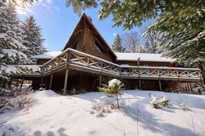 Une cabane en bois avec un porche couvert et des arbres recouverts de neige.