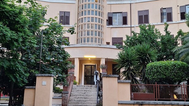 Un edificio a più piani con una sezione cilindrica centrale, diverse finestre e una scala che conduce all'ingresso.