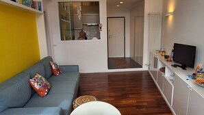 Un soggiorno moderno con un divano, un tavolo da pranzo e una cucina sullo sfondo.