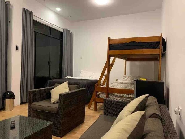 A room with a bunk bed, a sofa, a coffee table, and a TV.