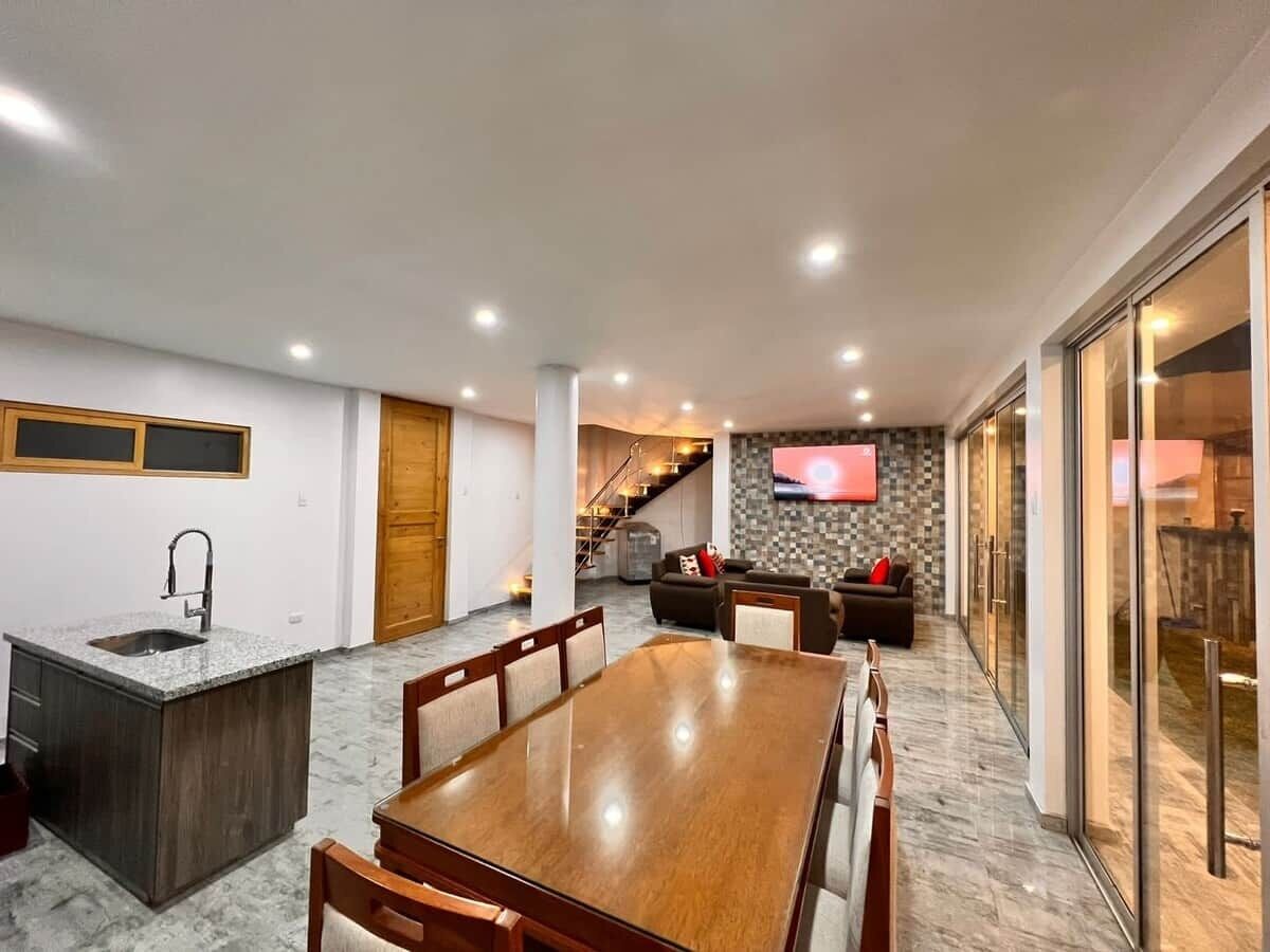 A modern kitchen with a dining area, a built-in island, and a TV mounted on the wall.