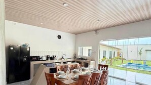 A modern kitchen with a dining area, a large window, and a view of a swimming pool. - Casa en Ica con piscina, parrilla y gran jardín (Ica)