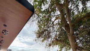 A modern outdoor patio with a pool, a dining table with chairs, and a tree. - Casa en Ica con piscina, parrilla y gran jardín (Ica)