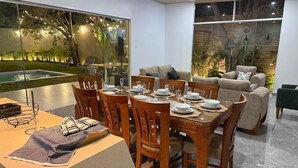 A dining area with a table set for four, surrounded by wooden chairs. - Casa en Ica con piscina, parrilla y gran jardín (Ica)